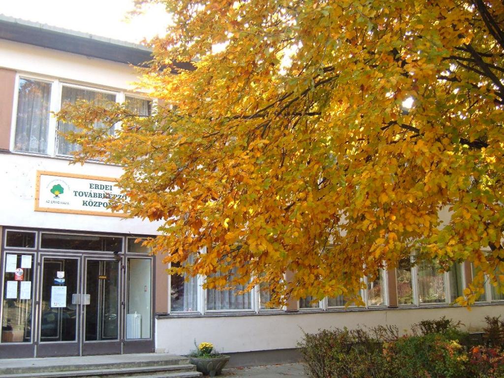 A főépület bejárata az Erdei továbbképző központ táblájával, ősszel, sárga lombú fa alatt